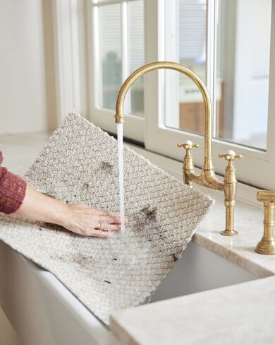 Person rinsing Hit The Road in Bone FLOR carpet tile stained with dirt in the sink. 